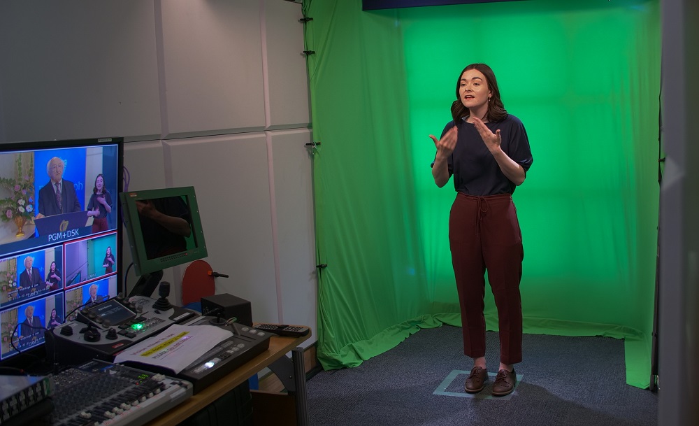 ISL interpreter interpreting before a green screen